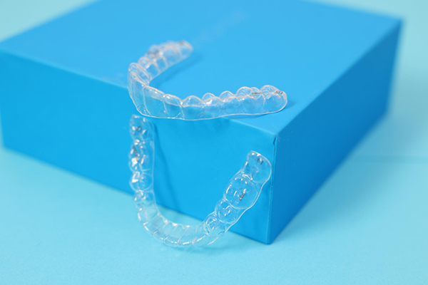 Clear aligners displayed on a blue box, linked to Invisalign orthodontic services in Westminster, London.
