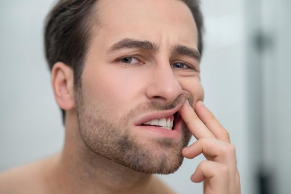 man with his finger in his mouth with a painful expression