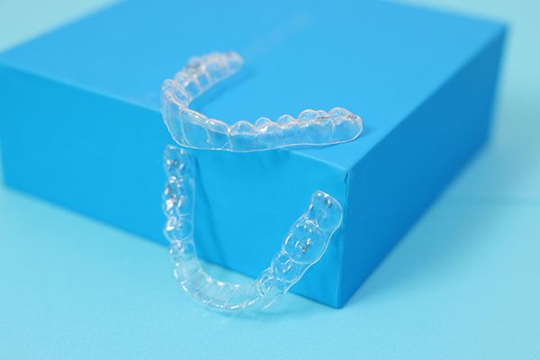 Clear aligners displayed on a blue box, linked to Invisalign orthodontic services in Westminster, London.