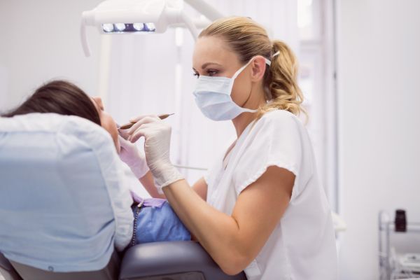 dental hygienist woman wearing a mask and checking a patient in a dental chair