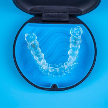 a clean aligner in its case on a blue background, the case is opened.