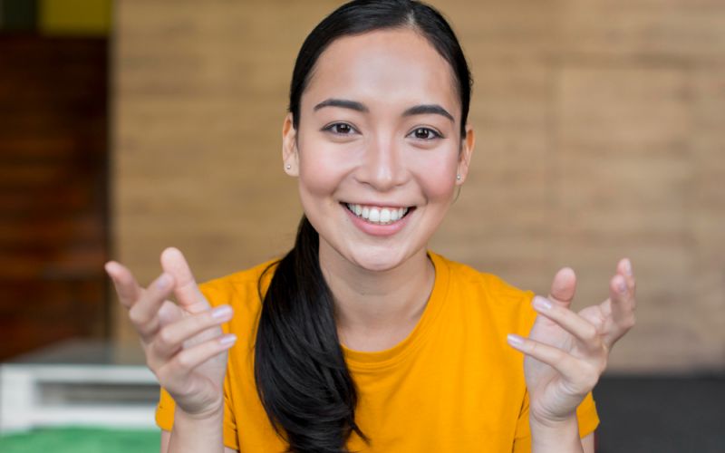  A smiling woman gestures with her hands, conveying enthusiasm and positivity.