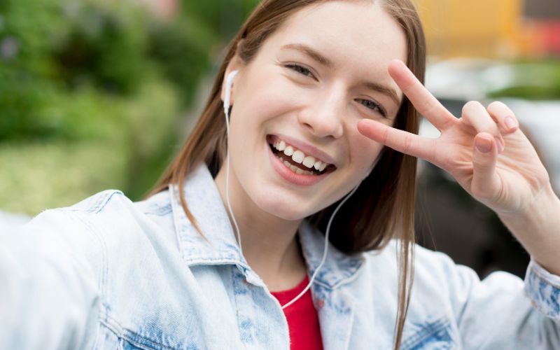 A young woman cheerfully showing a peace sign with her fingers.