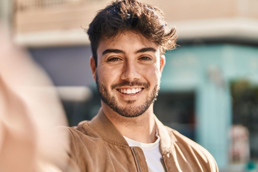 man in a brown shirt smiling at the camera depicting dental veneer treatment